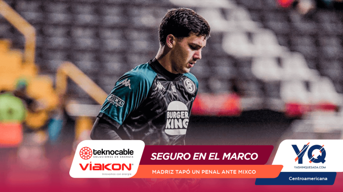 Soccer player in teal and black kit looking down, with a Burger King logo on the chest and a blurred stadium background.