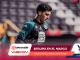 Soccer player in teal and black kit looking down, with a Burger King logo on the chest and a blurred stadium background.