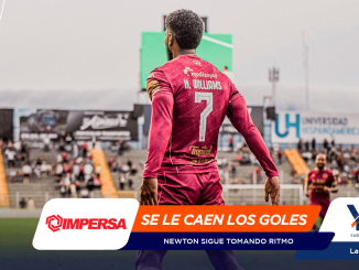 Soccer player in a pink jersey viewed from behind on a stadium field, with large promotional banners in the foreground.