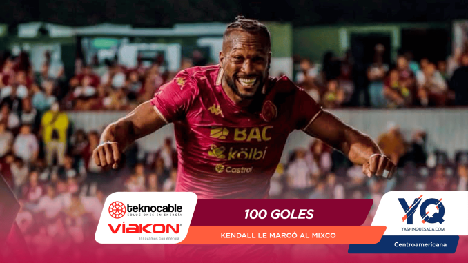 Male soccer player in a maroon jersey celebrates a goal with arms outstretched, smiling as fans cheer in the background (stadium scene).
