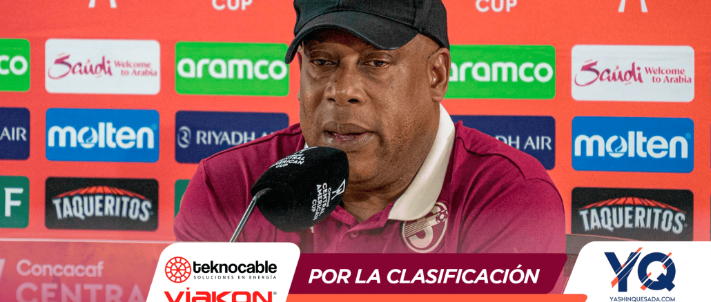 Man in a maroon polo and black cap speaks into a microphone at a press conference backdrop featuring Central American Cup logos and sponsors.