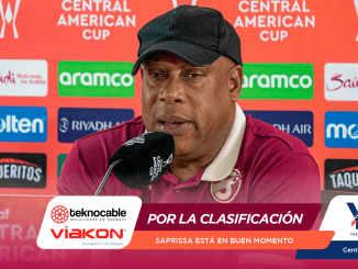 Man in a maroon polo and black cap speaks into a microphone at a press conference backdrop featuring Central American Cup logos and sponsors.