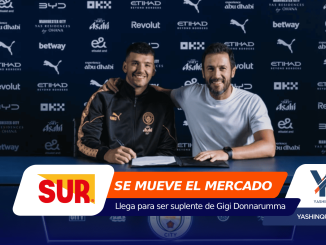 Two men sit at a desk signing a document, smiling, in front of a dark sponsor backdrop with logos.